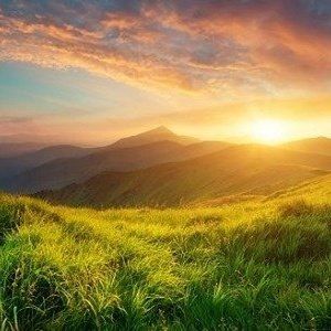 Sunset in the mountains over a grassy field